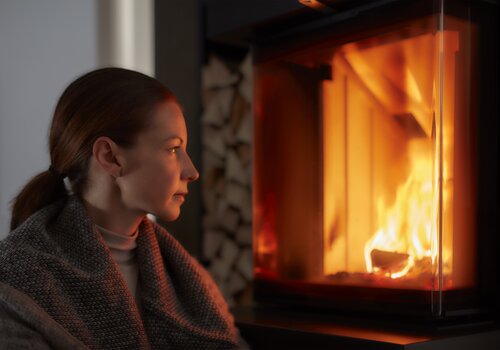 Žena se dívá do hořícího krbu