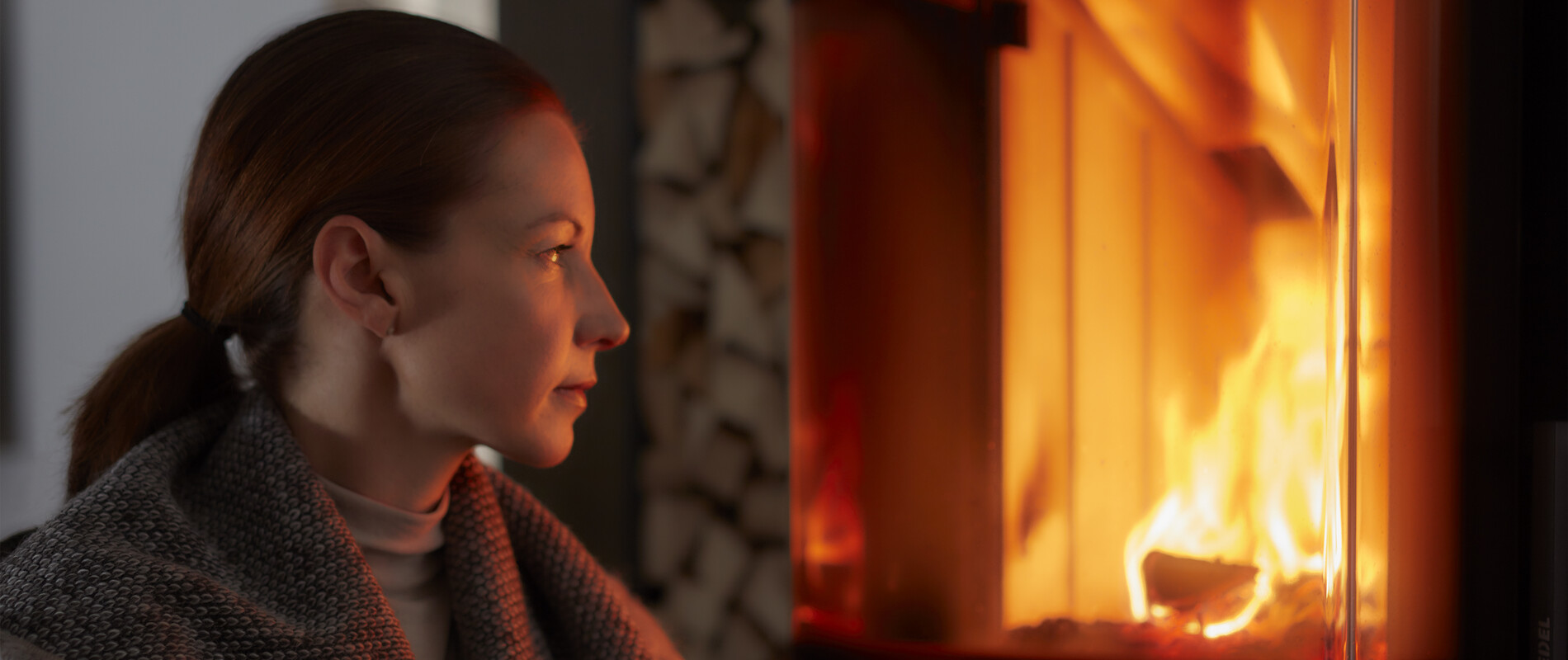 Kandallóban logobó tüzet néző nő