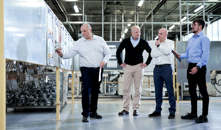 Eine Gruppe von Personen in einer Schiedel Edelstahl Produktionshalle, die ein Projekt planen